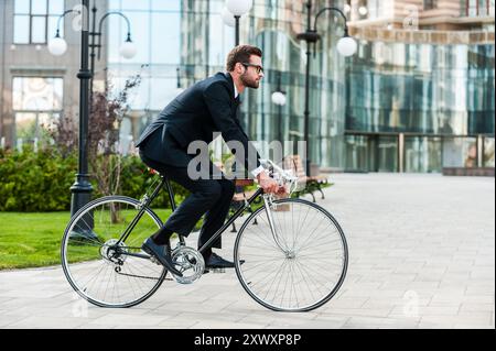 Überall von seinem Fahrrad. Seitenansicht der junge Unternehmer freuen uns auf dem Fahrrad Stockfoto