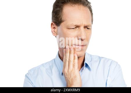 Leiden an Zahnschmerzen. Frustrierter reifer Mann, der das Gesicht berührt und Negativität ausdrückt, während er vor weißem Hintergrund steht Stockfoto