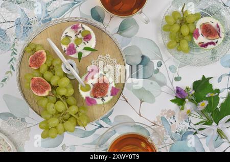 Teeparty mit Cupcakes und Früchten auf Plateau mit wilden Blumen, Tisch mit Blick von oben. Stockfoto