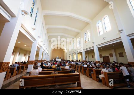 Medjugorje, Bosnien und Herzegowina - 15. Juli 2024: Ein Kircheninnenraum, in dem während eines Gottesdienstes eine Gemeinde untergebracht ist und durch das Tageslicht durchleuchtet wird Stockfoto