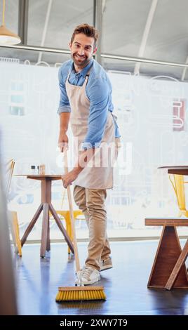 Glücklicher Mann, Porträt und Kellner mit Besen im Restaurant für Reinigung, Hygiene oder Bodenträger. Junge männliche Person oder Putzfrau mit einem Lächeln oder einer Schürze Stockfoto