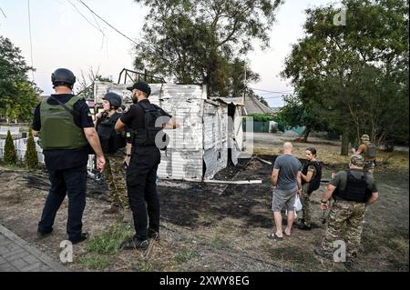 MALOKATERYNIVKA, UKRAINE - 20. AUGUST 2024 - Strafverfolgungsbehörden befinden sich vor dem Levada-Kindercafé im zentralen Park, das durch einen russischen Artilleriegutanschlag beschädigt wurde, im Dorf Malokateryniwka, Region Zaporischzhia, Südostukraine. Als Folge des russischen Angriffs starben zwei Menschen, darunter ein 14-jähriger Junge. Sechs Kinder sind im Krankenhaus, zwei Jungen leiden an Rückenmarkverletzungen. Stockfoto