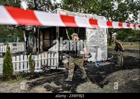 MALOKATERYNIVKA, UKRAINE - 20. AUGUST 2024 - Strafverfolgungsbehörden befinden sich vor dem Levada-Kindercafé im zentralen Park, das durch einen russischen Artilleriegutanschlag beschädigt wurde, im Dorf Malokateryniwka, Region Zaporischzhia, Südostukraine. Als Folge des russischen Angriffs starben zwei Menschen, darunter ein 14-jähriger Junge. Sechs Kinder sind im Krankenhaus, zwei Jungen leiden an Rückenmarkverletzungen. Stockfoto