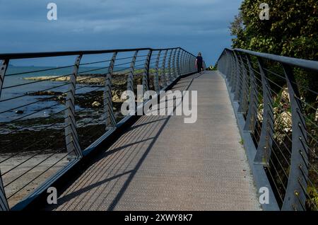 Fußgängerbrücke über die felsige Küste in County unten mit diagonalen Schatten, die von der Sonne geworfen werden Stockfoto