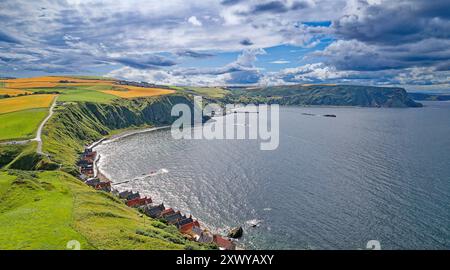 Crovie Aberdeenshire Schottland Gerstenfelder und Regenwolken im Sommer über den roten Dächern der Häuser Stockfoto