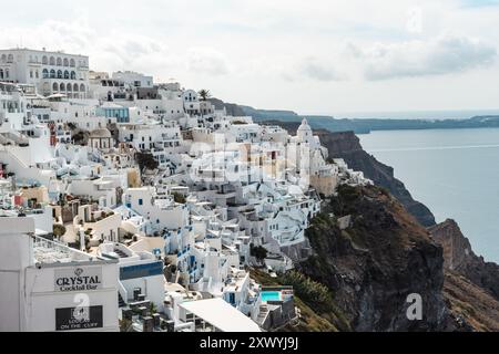 Santorin, Griechenland - 8. Oktober 2019: Weiß getünchte Gebäude Klammern sich an Klippen über der Ägäis. Stockfoto