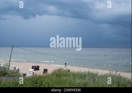 28.07.2024, Heringsdorf, Usedom, Mecklenburg-Vorpommern, Deutschland, Europa - Dunkle Wolken ziehen ueber den leeren Sandstrand des Ostseebads Heringsdorf und einem Spaziergaenger am Ufer auf der beliebten deutschen Urlaubsinsel Usedom an der Ostsee. *** 28 07 2024, Heringsdorf, Usedom, Mecklenburg-Vorpommern, Deutschland, Europa Dunkle Wolken ziehen über den leeren Sandstrand des Ostseebades Heringsdorf und ein Wanderer am Ufer auf der beliebten deutschen Urlaubsinsel Usedom an der Ostsee Stockfoto