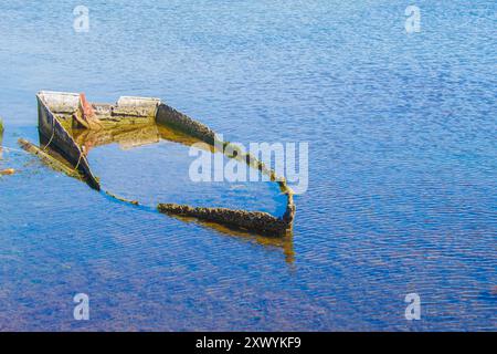Das alte Fischerboot ist halb im Meer gesunken. Versunkenes Boot auf dem Friedhof verlassener Boote im Ebro-Delta. Das Konzept der Ruhe und Gelassenheit. Stockfoto