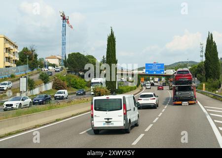 Nizza, Frankreich - 6. Juni 2023: Ein weißer Van fährt eine Autobahn in Südfrankreich entlang, vorbei an einem Autoträger mit zwei Autos. Es gibt noch andere Autos im Th Stockfoto