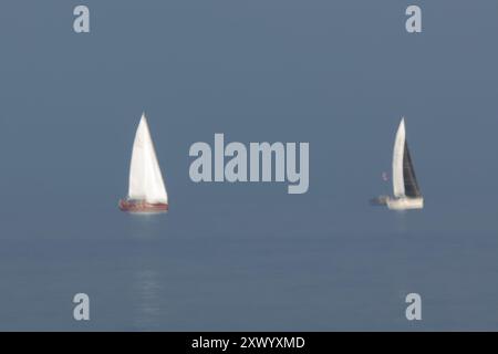 Segelboote fahren am 14. August 2024 über die Raritan Bay in der Gegend zwischen Staten Island und New Jersey. Eine lange Belichtung wurde verwendet, um Bewegungen aufzunehmen. Stockfoto