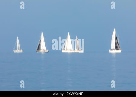 Segelboote fahren am 14. August 2024 über die Raritan Bay in der Gegend zwischen Staten Island und New Jersey. Eine lange Belichtung wurde verwendet, um Bewegungen aufzunehmen. Stockfoto