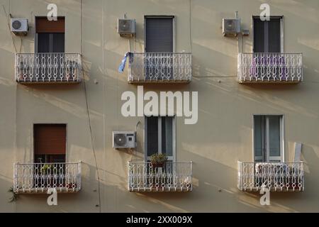 Kleine Appartementbalkone mit wandmontierter Klimaanlage werden am späten Nachmittag im Sommer in Europa gezeigt. Stockfoto