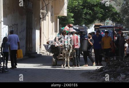 Die Palästinenser, die ihre Sachen tragen, sind auf dem Weg, in sicherere Gebiete zu wandern, nachdem die israelische Armee vor der Evakuierung gewarnt hat. Die Palästinenser, die ihre Sachen tragen, sind auf dem Weg, in sicherere Gebiete zu emigrieren, nachdem die israelische Armee vor der Evakuierung der Gebiete Abu Areef und Al-Mazra in Deir al-Balah, Gaza, am 21. August 2024 gewarnt hatte. Foto: Naaman Omar apaimages Dair EL-Balah Gazastreifen Palästinensische Gebiete 210824 Dair EL-Balah NAA 0028 Copyright: XapaimagesxNaamanxOmarxxapaimagesx Stockfoto