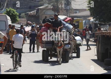 Die Palästinenser, die ihre Sachen tragen, sind auf dem Weg, in sicherere Gebiete zu wandern, nachdem die israelische Armee vor der Evakuierung gewarnt hat. Die Palästinenser, die ihre Sachen tragen, sind auf dem Weg, in sicherere Gebiete zu emigrieren, nachdem die israelische Armee vor der Evakuierung der Gebiete Abu Areef und Al-Mazra in Deir al-Balah, Gaza, am 21. August 2024 gewarnt hatte. Foto: Naaman Omar apaimages Dair EL-Balah Gazastreifen Palästinensische Gebiete 210824 Dair EL-Balah NAA 0039 Copyright: XapaimagesxNaamanxOmarxxapaimagesx Stockfoto