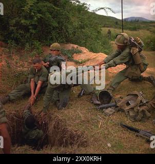 Vietnamkrieg. Operation 'Oregon', eine Such- und Zerstörungsmission, die von einem Infanteriezug der Truppe B, 1. Aufklärungsgeschwader, 9. Kavallerie, 1. Kavallerie-Division (Luftmobil), drei Kilometer westlich von Duc Pho, Provinz Quang Ngai, durchgeführt wird. Ein Infanteriker wird von Mitgliedern des Aufklärungszuges in einen Tunnel abgesenkt. April 1967. Stockfoto