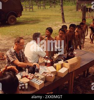 Vietnamkrieg. In einem abgelegenen thailändischen Dorf werden die Kinder von Mitgliedern eines Teams des Civic Action Center der US Air Force von der Nakom Phanom Air Base, Thailand, untersucht. Staff Sergeant Ray Varker (links) wird gezeigt, wie er die von Sergeant Charles Thorne angeforderten Arzneimittel vorbereitet, der die Kinder untersucht und die Medikamente bestimmt. Juni 1968 Stockfoto