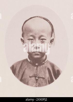 Vintage-Foto von männlichen Köpfen, Chinesen und Mongolien. Illustrations of Qing China, 1875 Foto eines Jungen der oberen oder höchsten Klasse, Sohn eines angesehenen Beamten des Kantons. Er ist ein feiner, attraktiver kleiner Kerl, seine braunen Augen strahlen vor Freundlichkeit und Intelligenz. Die Mandelform und die schräge Einstellung des Auges, die für die Einheimischen des Südens so charakteristisch sind, werden in diesem Bild gut dargestellt. Stockfoto