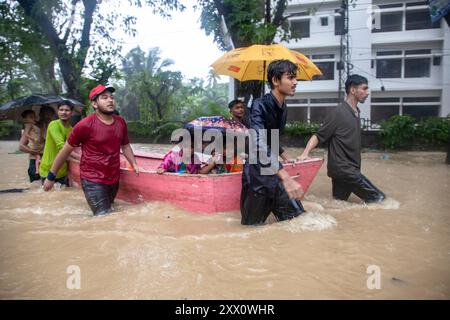 Feni, Chittagong, Bangladesch. August 2024. 21. August 2024, Feni, Bangladesch: Freiwillige im Gebiet Munsirhat im Bezirk Ã¢â‚¬''¹Feni''¹Ã¢â‚¬ der Division Chittagong von Bangladesch. Frauen und Kinder, die in der Flut gefangen sind, werden mit dem Boot in Sicherheit gebracht. Am Mittwoch (21. August) wurden die Gewässer der Flüsse Muhuri, Kahua und Ceylon um 86 cm über dem Gefahrenniveau fließend gesehen, Straßen und Häuser wurden durch das Waldwasser nicht verschont. Mehr als 200.000 Menschen von drei upazilas sind in der schrecklichen humanitären Katastrophe desorientiert. In dieser Situation sind diese Bereiche völlig ohne Elektronen Stockfoto