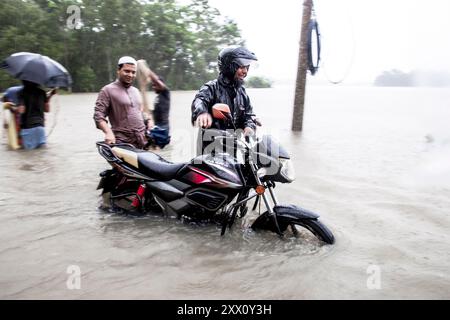 Feni, Chittagong, Bangladesch. August 2024. 21. August 2024, Feni, Bangladesch: Fußgänger waten durch Überschwemmungen bis zu ihren Taille und Knien in Sicherheit in Munsirhat-Gebiet des Bezirks Feni der Division Chittagong, Bangladesch. Am Mittwoch (21. August) wurden die Gewässer der Flüsse Muhuri, Kahua und Ceylon um 86 cm über dem Gefahrenniveau fließend gesehen, Straßen und Häuser wurden durch das Wasser im Wald nicht verschont. Mehr als 200.000 Menschen von drei upazilas sind in der schrecklichen humanitären Katastrophe desorientiert. In dieser Situation sind diese Gebiete völlig ohne Strom. (Guthaben Im Stockfoto