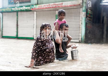 Feni, Chittagong, Bangladesch. August 2024. 21. August 2024, Feni, Bangladesch: Fußgänger waten durch Überschwemmungen bis zu ihren Taille und Knien in Sicherheit in Munsirhat-Gebiet des Bezirks Feni der Division Chittagong, Bangladesch. Am Mittwoch (21. August) wurden die Gewässer der Flüsse Muhuri, Kahua und Ceylon um 86 cm über dem Gefahrenniveau fließend gesehen, Straßen und Häuser wurden durch das Wasser im Wald nicht verschont. Mehr als 200.000 Menschen von drei upazilas sind in der schrecklichen humanitären Katastrophe desorientiert. In dieser Situation sind diese Gebiete völlig ohne Strom. (Guthaben Im Stockfoto