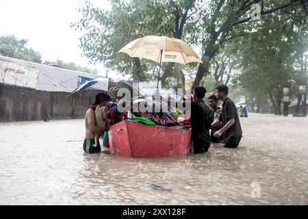 Feni, Chittagong, Bangladesch. August 2024. 21. August 2024, Feni, Bangladesch: Freiwillige im Gebiet Munsirhat des Distrikts Feni der Division Chittagong von Bangladesch. Frauen und Kinder, die in der Flut gefangen sind, werden mit dem Boot in Sicherheit gebracht. Am Mittwoch (21. August) wurden die Gewässer der Flüsse Muhuri, Kahua und Ceylon um 86 cm über dem Gefahrenniveau fließend gesehen, Straßen und Häuser wurden durch das Waldwasser nicht verschont. Mehr als 200.000 Menschen von drei upazilas sind in der schrecklichen humanitären Katastrophe desorientiert. In dieser Situation sind diese Gebiete völlig ohne Strom. (Cre Stockfoto