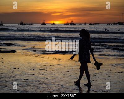 Frau, die barfuß am Strand bei Sonnenuntergang geht, Tamarindo, Costa Rica Stockfoto