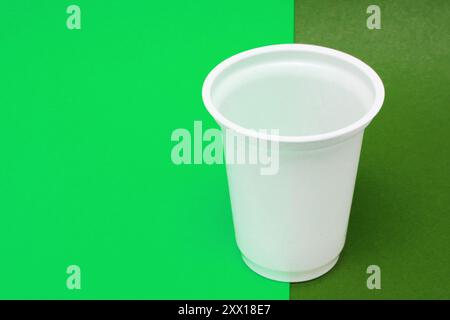Plastikbecher auf Hintergrund von zwei grünen Farben. Stockfoto