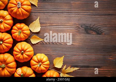 Thanksgiving- und Herbstdekorationskonzept aus Herbstblättern und Kürbis auf hölzernem Hintergrund. Flach, Draufsicht mit Kopierraum. Stockfoto
