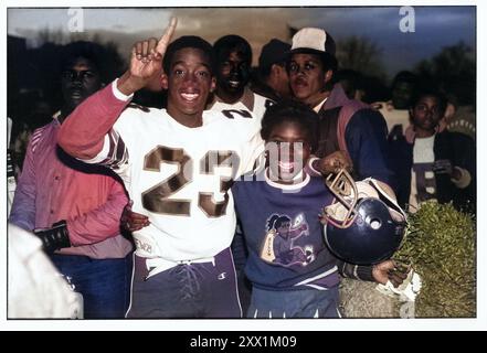 Nach dem Gewinn des Spiels posierte ein Fußballspieler der Bayside High School für ein Foto mit seiner Cheerleader-Freundin. 1983 in Brooklyn, New York. Dieses Foto wurde ursprünglich in Schwarzweiß erstellt und in Photoshop in Farbe umgewandelt Stockfoto