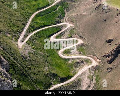 Aus der Vogelperspektive auf eine gewundene Bergstraße, den Kalmak Ashuu Pass, durch üppiges Grün in Kirgisistan, Zentralasien, Asien Stockfoto