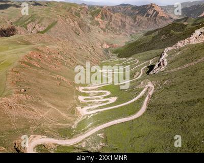 Aus der Vogelperspektive auf eine gewundene Bergstraße, den Kalmak Ashuu Pass, durch üppiges Grün in Kirgisistan, Zentralasien, Asien Stockfoto