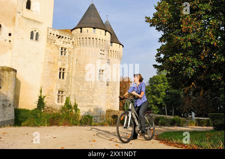 Junge Frau radelt vor dem Schloss St-Jean, Nogent-le-Rotrou, Parc naturel Regional du Perche, Eure-et-Loir, Cengre-Val-de-Loire, Frankreich Stockfoto