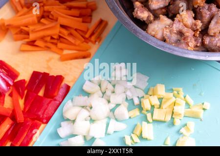 In einer Schüssel werden gebratene, gehackte Schweinestücke neben Karotten und Zwiebeln für das weitere Kochen von Schweinefleisch in einer süß-sauren Sauce gemäß zubereitet Stockfoto