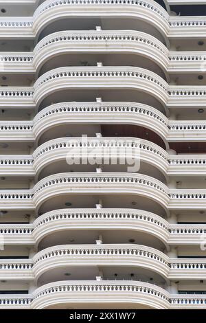 Abstrakter Architekturhintergrund. Nahaufnahme der Hochhausfassade mit sich wiederholenden Mustern von geschwungenen Balkonen, die architektonische Gestaltung zeigen Stockfoto