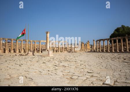 Das Oval Forum und Cardo Maximus im antiken Jerash. Historisches Wahrzeichen der römischen Architektur mit jordanischer Flagge in Nordjordanien. Stockfoto