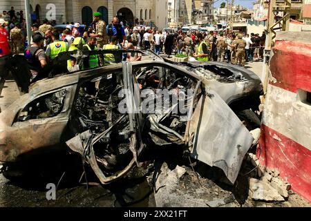 Sidon, Libanon. August 2024. Menschen versammeln sich in der Nähe eines Fahrzeugs, das am 21. August 2024 von Raketen einer israelischen Drohne in Sidon, Libanon, zerstört wurde. Eine israelische Drohne feuerte am Mittwochmorgen zwei Luft-Boden-Raketen auf einen zivilen SUV am Südeingang der Stadt Sidon ab und tötete einen Führer der Al-Aqsa Märtyrer-Brigaden, dem bewaffneten Flügel der Palästinensischen Nationalen Befreiungsbewegung (Fatah), sagten libanesische Militärquellen gegenüber Xinhua. Quelle: Ali Hashisho/Xinhua/Alamy Live News Stockfoto