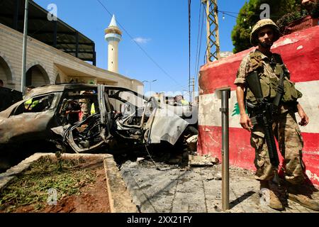 Sidon, Libanon. August 2024. Ein Soldat steht in der Nähe eines Fahrzeugs, das am 21. August 2024 durch Raketen einer israelischen Drohne in Sidon, Libanon, zerstört wurde. Eine israelische Drohne feuerte am Mittwochmorgen zwei Luft-Boden-Raketen auf einen zivilen SUV am Südeingang der Stadt Sidon ab und tötete einen Führer der Al-Aqsa Märtyrer-Brigaden, dem bewaffneten Flügel der Palästinensischen Nationalen Befreiungsbewegung (Fatah), sagten libanesische Militärquellen gegenüber Xinhua. Quelle: Ali Hashisho/Xinhua/Alamy Live News Stockfoto