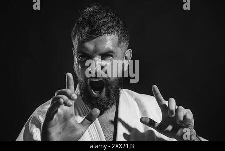 Nahaufnahme Porträt schreiender Karate Mann in Kampfposition bereit zum Training. Wütender Karate-Mann im Kimono, der Kampfkunst übt. Karate-Kämpfer Stockfoto