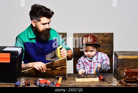 Vater bringt dem kleinen Sohn bei, Handwerkzeuge in der Werkstatt zu benutzen. Vater verbringt Zeit mit Sohn in der Werkstatt und trainiert Kind, um Handinstrumente zu benutzen. Kind Stockfoto