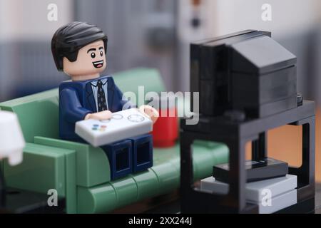 Tambow, Russische Föderation - 21. August 2024 Eine Minifigur eines Lego-Geschäftsmannes sitzt auf einer Couch und spielt Videospiele. Stockfoto
