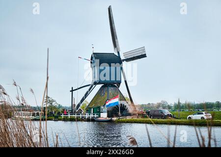 Kinderdijk, Rotterdam, Niederlande - 11. April 2024: Historische Windmühlen und ein Fluss, der in Kinderdijk vorbeifließt. 19 Windmühlen wurden um 1740 gebaut Stockfoto