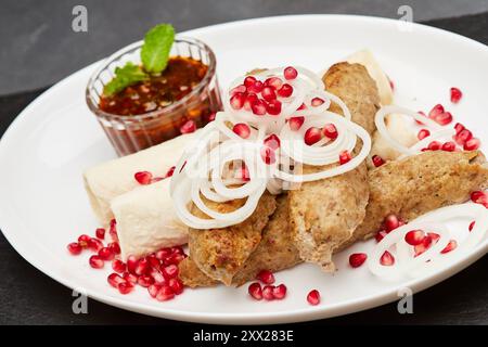 Traditioneller gegrillter Kebab mit Granatapfel, Zwiebeln und scharfer Sauce für ein köstliches kulinarisches Erlebnis Stockfoto