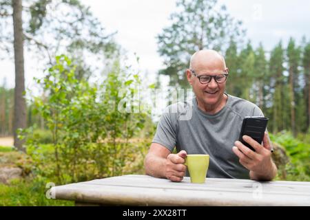 Senior Finn Mann mit Mobiltelefon im Freien in einem skandinavischen Waldsommer in Finnland Konzept Stockfoto