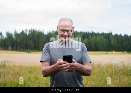 Senior Finn Mann mit Mobiltelefon im Freien in einem skandinavischen Waldsommer in Finnland Konzept Stockfoto