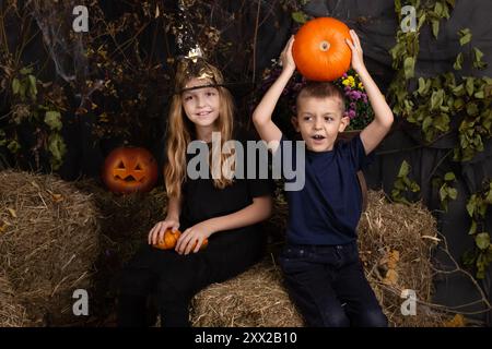 Glückliche Bruder und Schwester an Halloween. Lustige Kinder in Karnevalskostümen drinnen. Fröhliche Kinder spielen mit Kürbissen Stockfoto