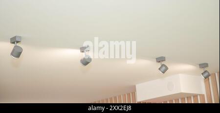 Kassettenmontierte Klimaanlage und moderne Lampe an der weißen Decke. Luftkanal-Klimaanlage für zu Hause oder im Büro. Stockfoto