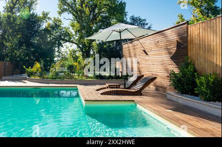 Swimmingpool in moderner privater Villa mit Liegestühlen, Palmen und Sonnenschirm Stockfoto