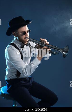 Professioneller Musiker, der Trompete auf dunklem Hintergrund spielt Stockfoto