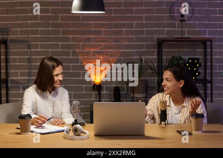 Schöne junge Frauen, die nachts Podcasts im Studio aufnehmen Stockfoto