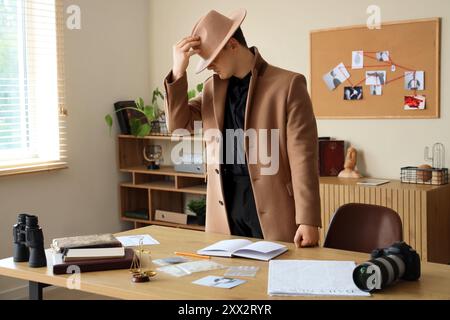 Männlicher Detective in der Nähe des Tisches im Büro Stockfoto